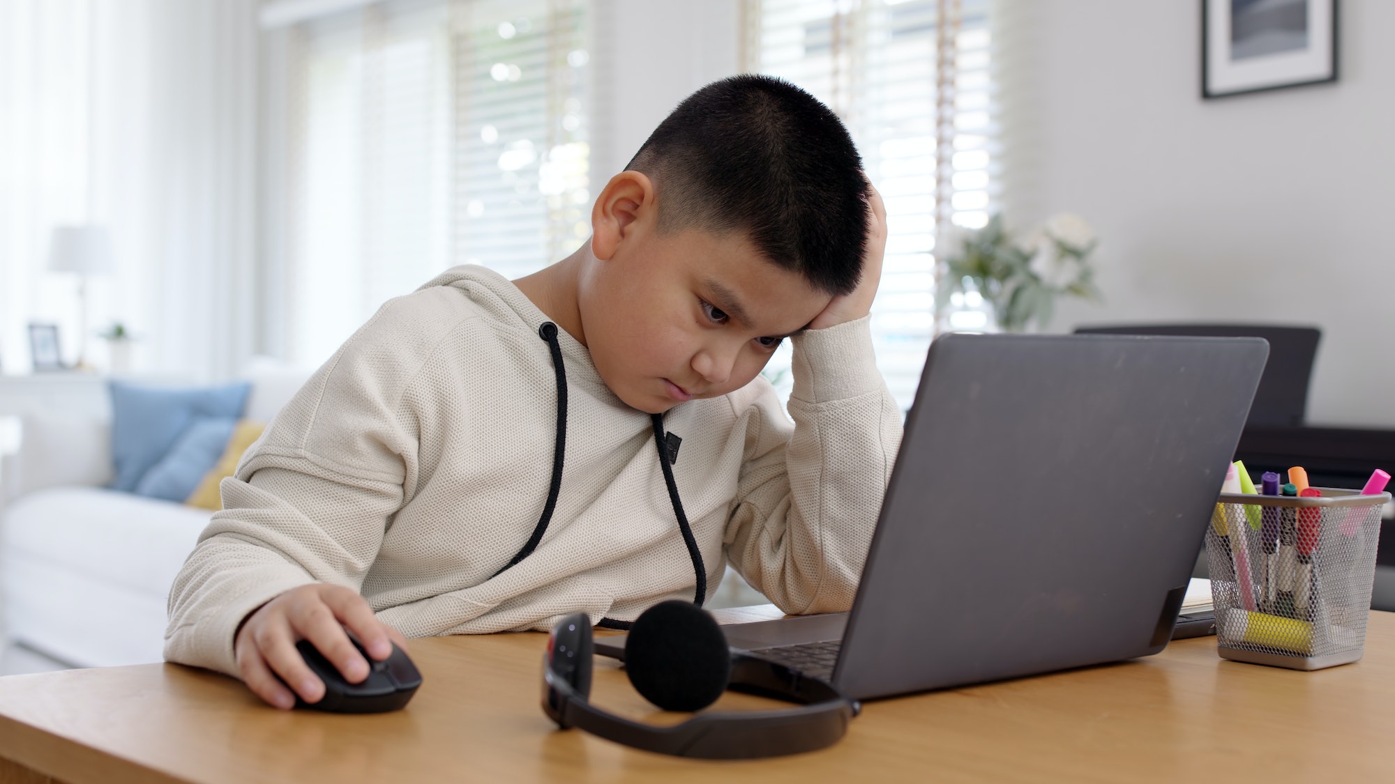 Young asia boy kid sit on desk look at computer notebook feeling bored tired